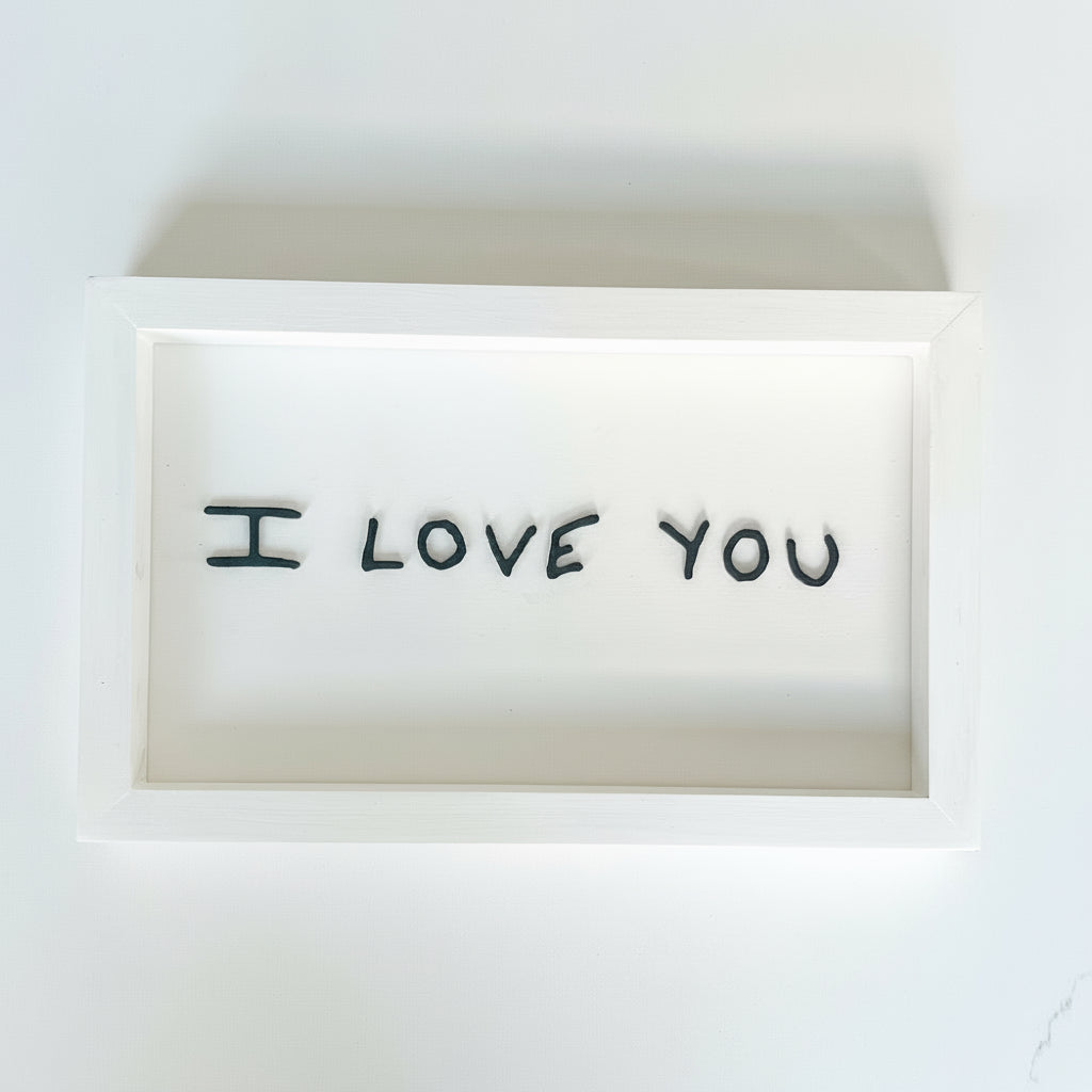 White sign with handwritten 'I LOVE YOU' text on a white background