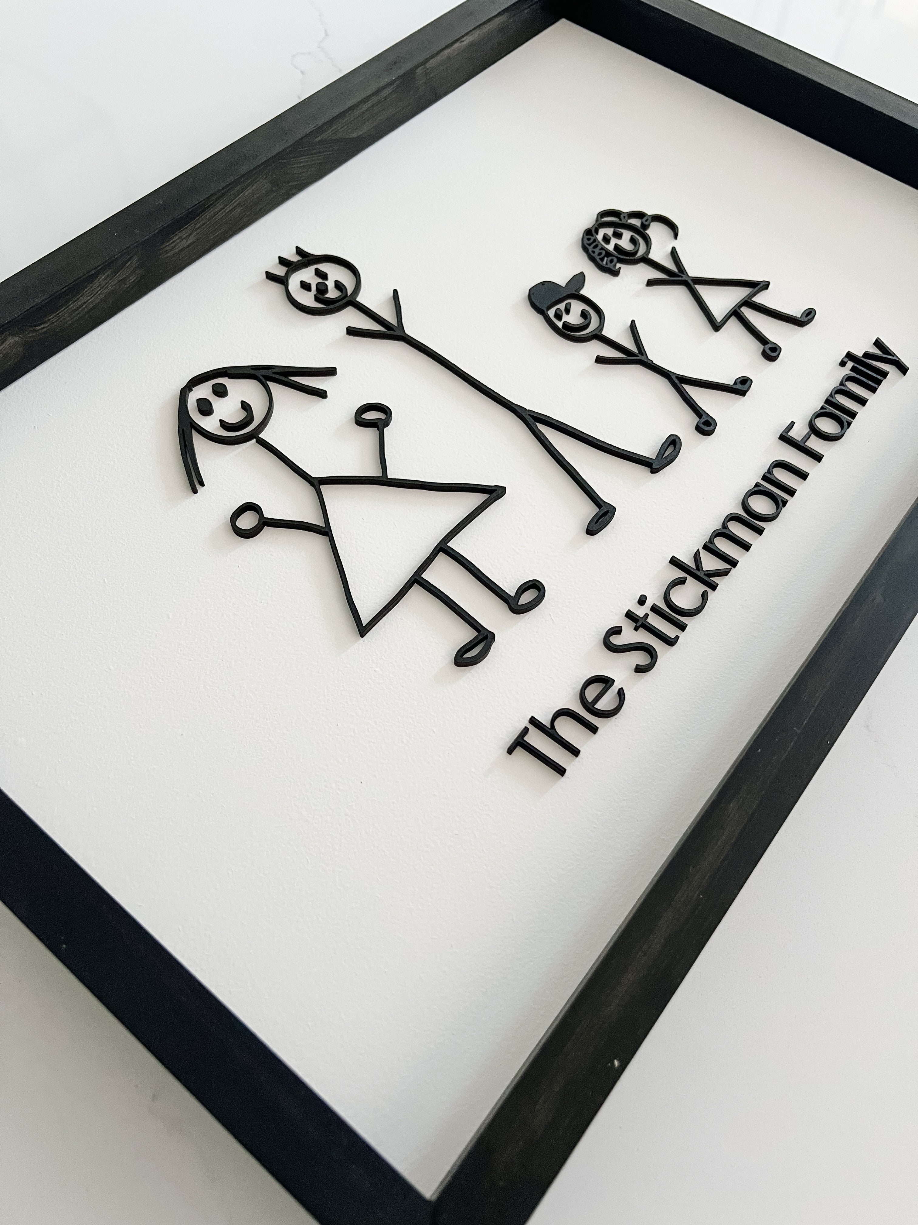 Framed artwork with stick figure family design and 'The Stickman Family' text.