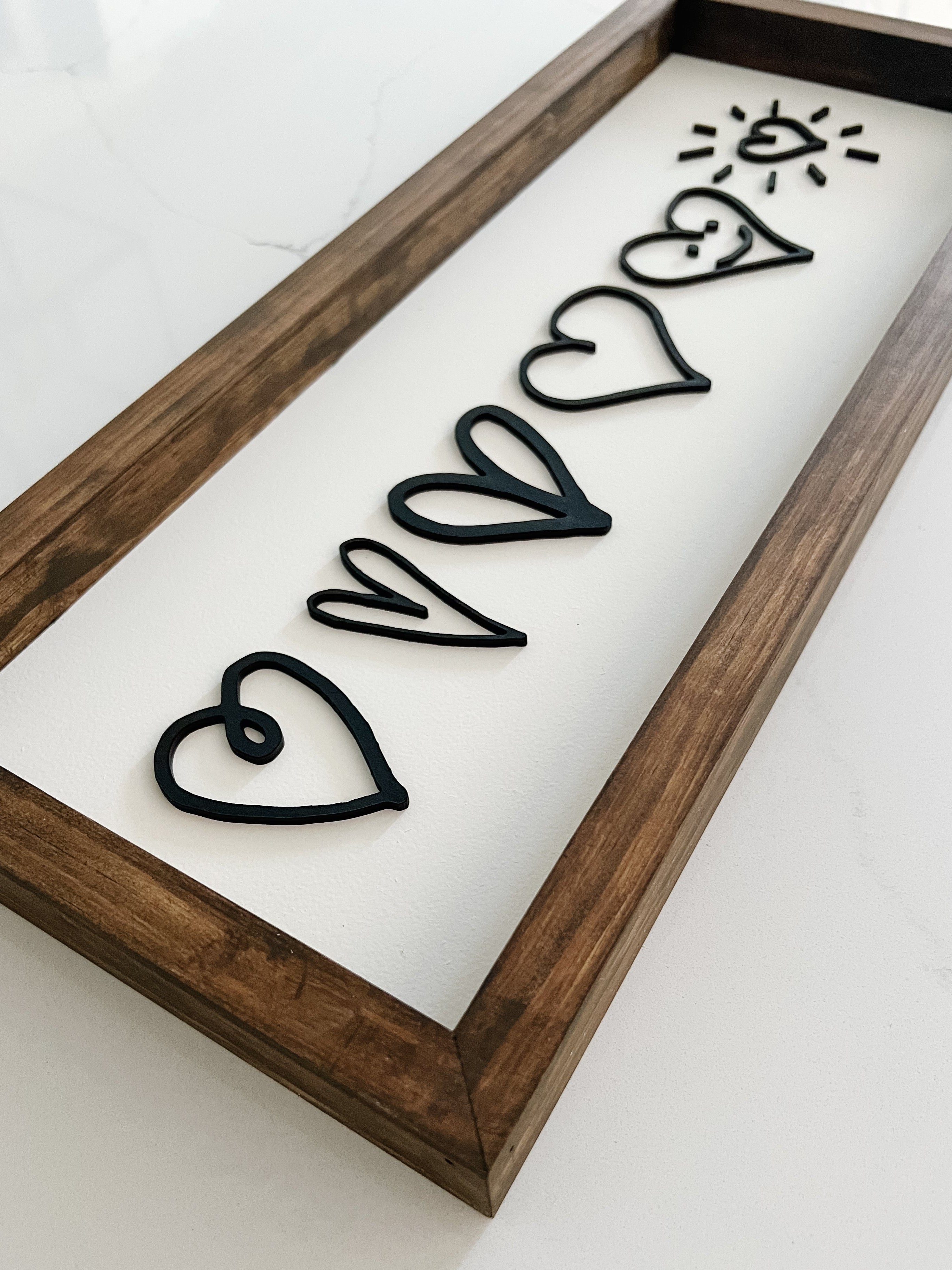 Decorative wall art with black heart shapes on a white background, framed in wood.