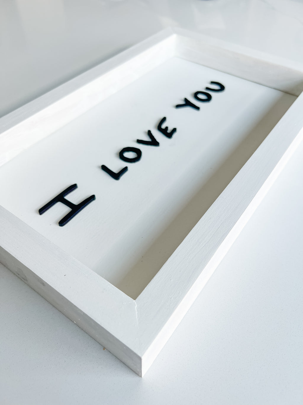 White rectangular object with 'I LOVE YOU' text on a light gray background