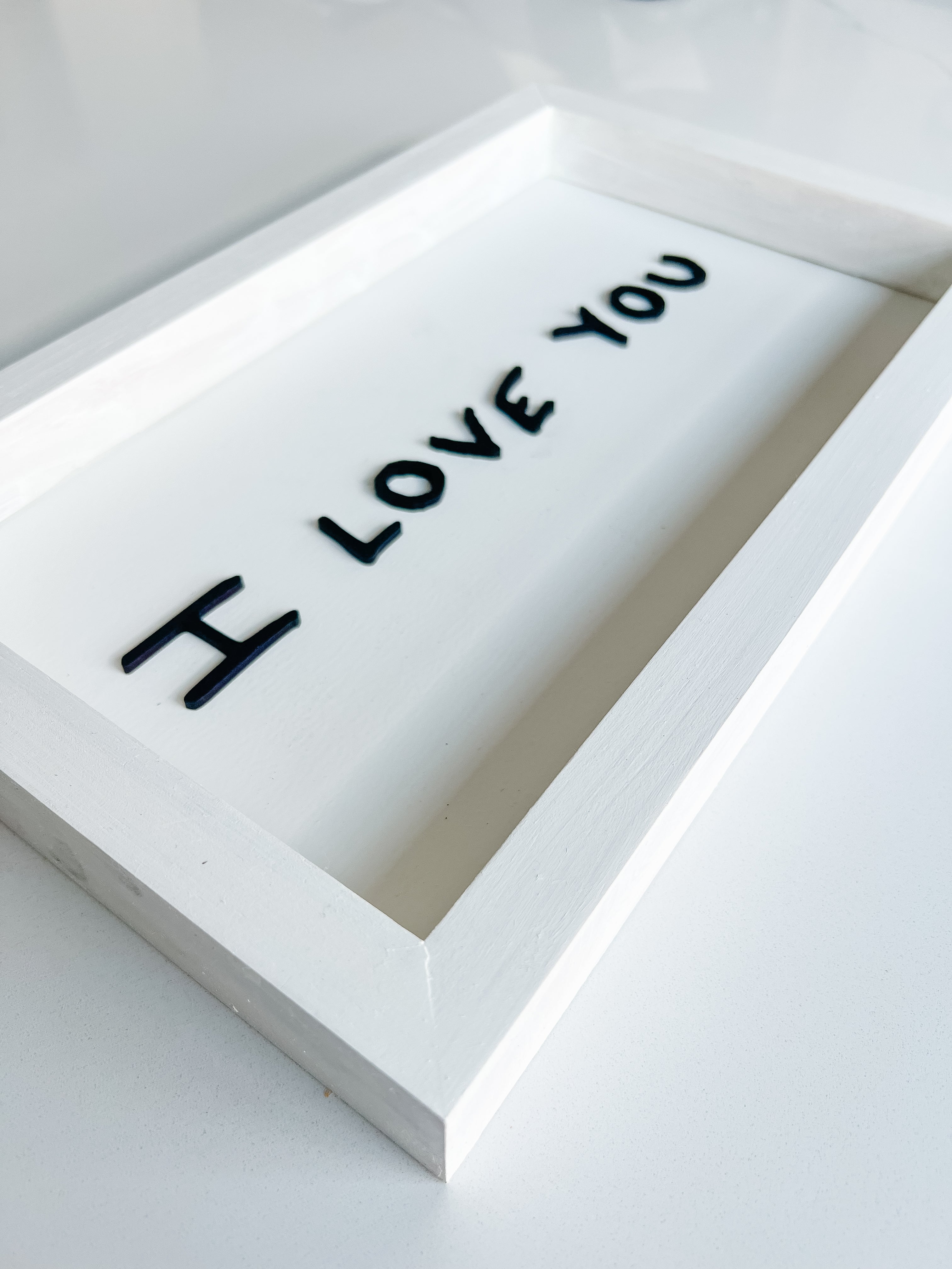 White rectangular object with 'I LOVE YOU' text on a light gray background