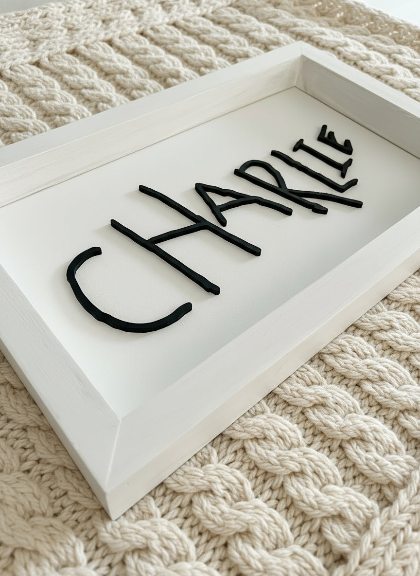 Black 'CHARLIE' nameplate on a white surface