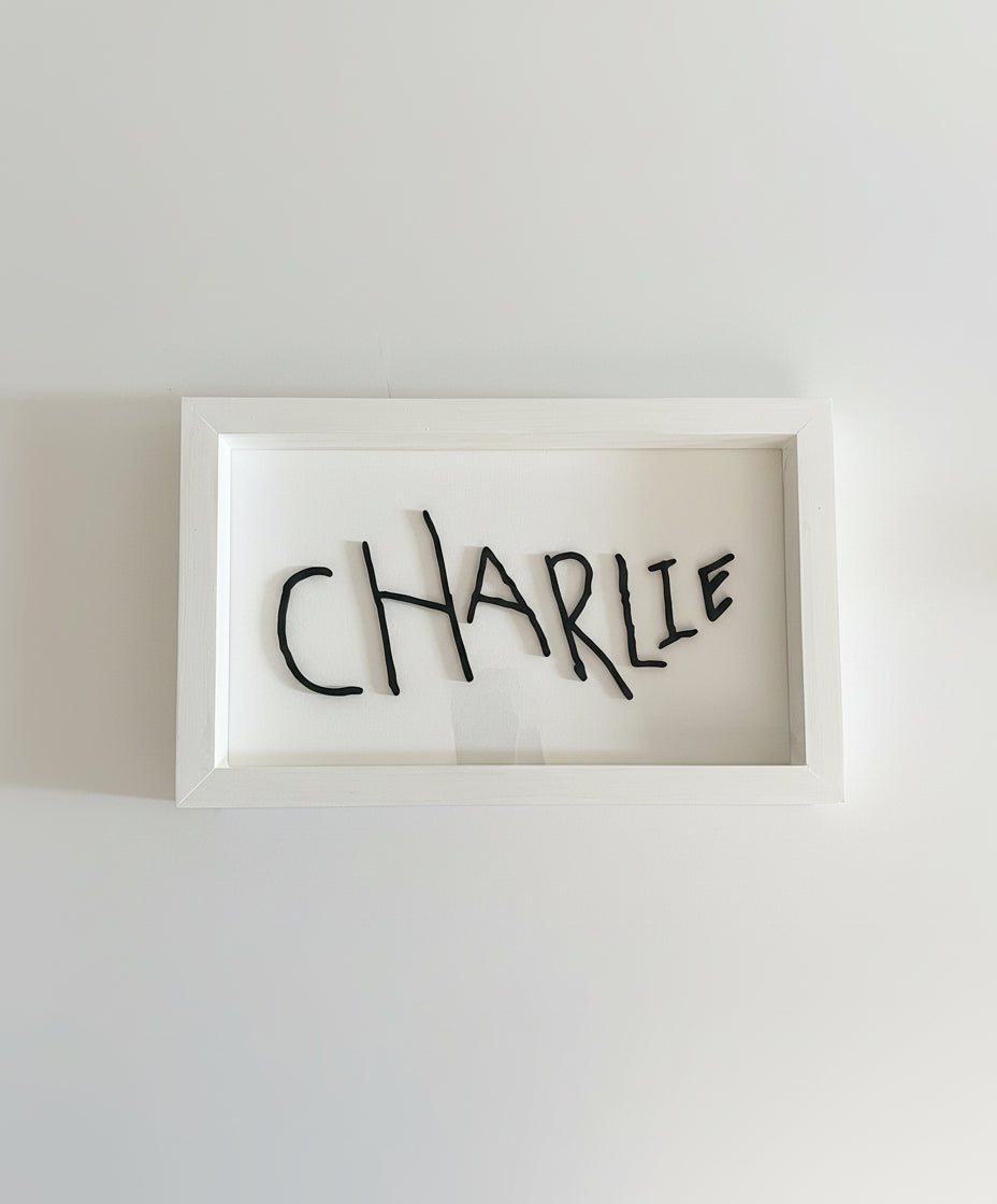 Framed artwork with the name 'CHARLIE' on a plain background