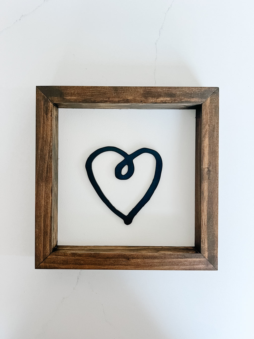 Framed artwork of a black heart on a white background